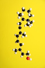 Molecule of retinol (vitamin A) on yellow background. Chemical model