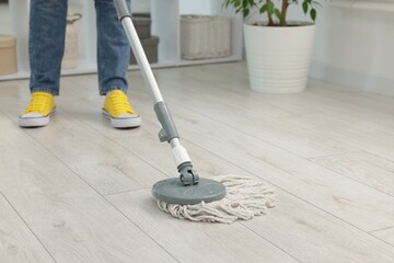 Woman cleaning floor with string mop indoors, closeup