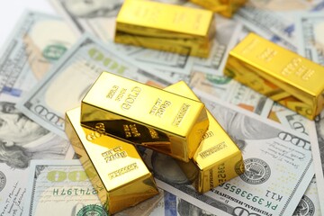 Shiny gold bars on dollar banknotes, closeup