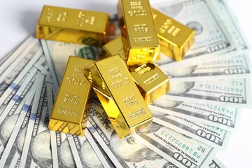 Shiny gold bars and dollar banknotes on white background, closeup