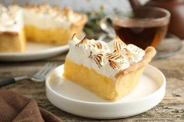 Piece of delicious pie with browned meringue on wooden table, closeup