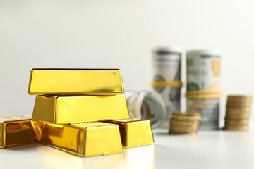 Shiny gold bars and money on light background, selective focus