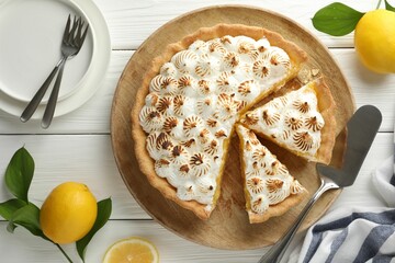 Flat lay composition with delicious meringue pie and lemons on white wooden table