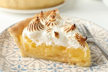 Piece of delicious pie with browned meringue and fork on white table, closeup
