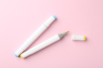 Two double sided markers on pink background, flat lay