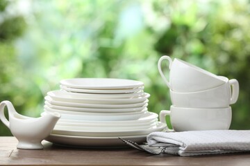 Clean dishware on wooden table against blurred background. Space for text