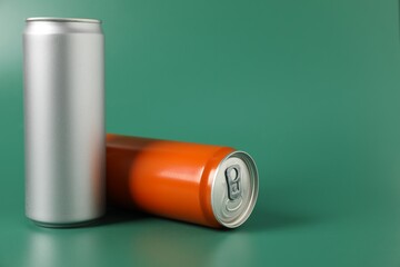 Two aluminium cans of beverage on green background, space for text