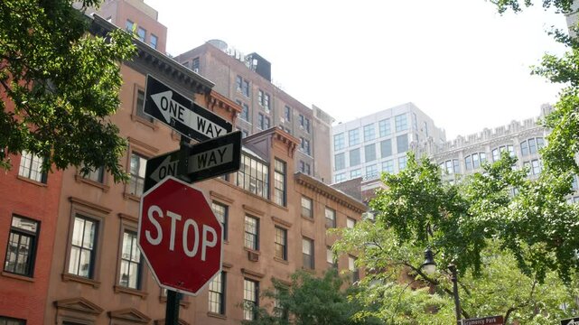 New York City oneway crossroad, Stuyvesant street intersection one way arrow. Manhattan Midtown residential building architecture, United States real estate. Red brick house wall, red stop road sign.