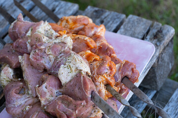 A close-up view of seasoned, marinated meat threaded onto metal skewers, ready for grilling. The mix of different spices and herbs creates a visually appealing texture