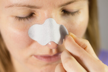 Woman applying nose pore strips for blackhead remove. Deep cleansing with charcoal. The treatment...