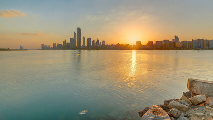 Fototapeta premium Abu Dhabi city skyline on sunrise time with water reflection timelapse.