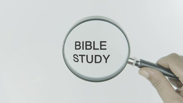 Bible Study text or word highlighted by a magnifying glass in a hand on a white background, symbolizing learning, faith, and spiritual growth