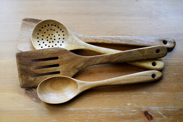 A collection of wooden kitchen utensils, including spoons and spatulas, arranged on a wooden surface