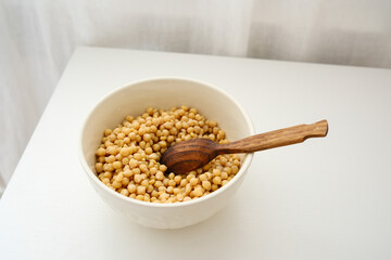 Dry raw chickpeas soaking in water before cooking on white table.