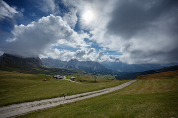 Majestic clouds hover over the Dolomites near Seceda, showcasing vibrant landscapes and serene mountain trails