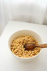 Dry raw chickpeas soaking in water before cooking on white table.
