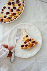 A beautiful dessert display with a piece of cherry pie on white plate holding by hand of woman.