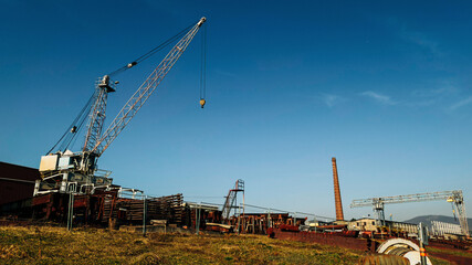 Fototapeta premium Large industrial crane at an old construction site with rusted metal beams