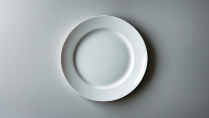Simple white plate placed on a light grey surface emphasizing minimalism in table settings