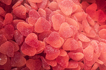 Volumetric background of jelly heart candies coated in sugar grains vibrant red and orange colors...