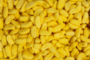 Background of yellow gelatin candies with a soft sugary coating and smooth texture forming a bright and uniform composition with a vibrant lemon-colored surface