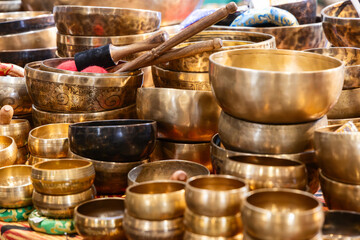 Assortment of handmade Tibetan singing bowls crafted from metal with engraved patterns and wooden strikers placed on a market stall