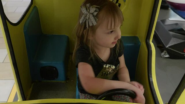 Little Girl Playing in Yellow Kiddie Ride Car