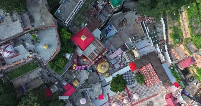 Aerial anticlockwise top view of the Jawalamukhi Temple complex in Himachal Pradesh, beautifully lit by the warm evening glow, highlighting the temple&rsquo;s golden domes and surrounding architecture.