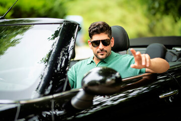 Mid aged man sitting in his convertible car and driving