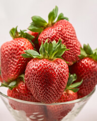 A clear glass bowl filled with fresh, plump strawberries
