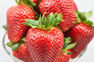 A clear glass bowl filled with fresh, plump strawberries

