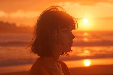 Fototapeta premium Woman Silhouetted Against Vibrant Sunset Over Ocean Waves at Beach
