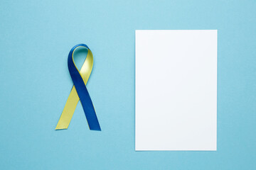 A yellow and blue awareness ribbon, symbolizing World Down Syndrome Day. White notebook mockup