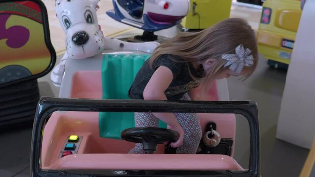 Little Girl Playing in Pink and White Kiddie Ride Car