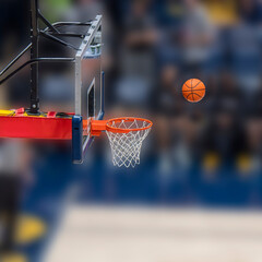 The image captures a basketball suspended mid-air as it approaches the hoop. The hoop is secured to a backboard, and the net hangs in anticipation of the ball's arrival.  © dfriend150
