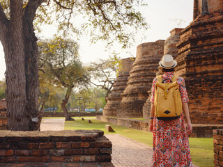 Young female tourist in dress exploring historic park of Ayutthaya, Thailand. Surrounded by ancient...