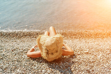 Beach Relaxation woman lies on a pebble beach, legs raised, and arms spread out. The concept of travel, vacation at sea