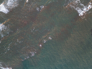 View of ocean waves crashing against rocky shoreline at sunset