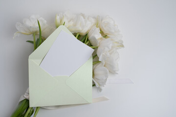 Mockup of white paper invitation card with envelope and white flowers, mockup with copy space.
