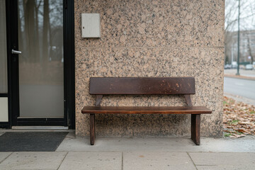 A wooden bench is sitting on the sidewalk in front of a building