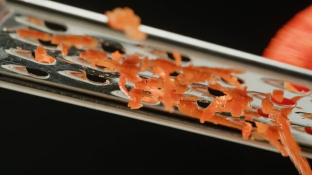 Carrot macro, Woman hands with a grater grate carrots on the wooden board, chef cooking polish potato pancakes in the kitchen. Healthy eating and lifestyle. 