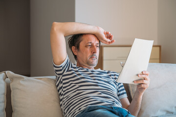 Man reading instruction manual paper at home