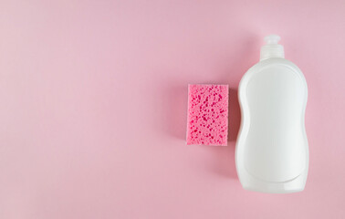 White bottle of dishwashing liquid and sponge on pink background with copy space. Top view.