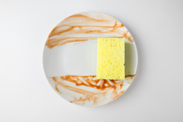 White dirty plate with red sauce and sponge for cleaning dishes isolated on white background. Cleaning concept.