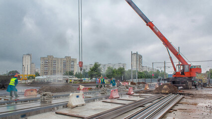 Orange construction telescopic crane unloading tram rails from truck timelapse.