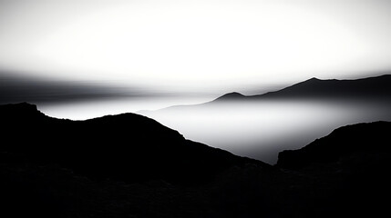 A black and white photo of a mountain range with a foggy sky