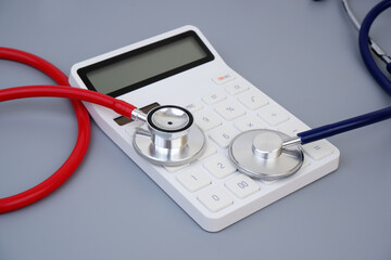 Choosing medical clinic and hospital concept. Cost of medical service. Different stethoscopes and calculator on gray background.