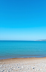 A beach view with a blue ocean and a sandy shore.