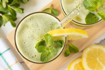 Glass of fresh lemonade with mint on kitchen table. Top view. Healthy summer blended drink.