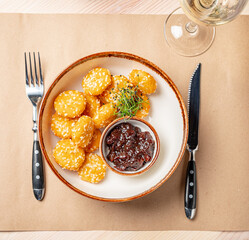 A plate of golden sesame balls accompanied by a dark dipping sauce awaits enjoyment